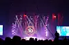 Konsertscene med lilla lys, en stor 30-logo og publikum i silhuett.