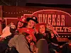 Gruppe personer poserer under rødt scenelys foran et banner.