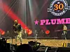 Plumbo spiller på en opplyst scene med jubileumslogo i bakgrunnen.