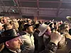 Brenton Bersin blant en folkemengde med cowboyhatter på et innendørs arrangement.
