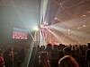 Konsertpublikum foran en scene med sterke lysstråler og videoskjermer.