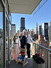 Tre personer på en balkong med utsikt over New Yorks skyline.