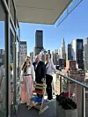 Tre personer på en balkong med utsikt over New Yorks skyline.