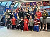 Unge fotballspillere og trenere poserer sammen i en innendørs idrettshall.