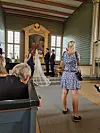 Brudepar ved alteret under en bryllupsseremoni i en historisk, rikt dekorert sal.