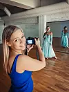 Kvinne fotograferer en modell i turkis kjole i et dansestudio.