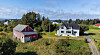 Rødt uthus og hvitt hus i et grønt kystlandskap med fjord i bakgrunnen.