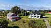 Rødt uthus og hvitt hus i et grønt kystlandskap med fjord i bakgrunnen.