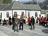 Folkemengde foran en hvit trekirke med røde og hvite flagg.