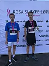 To unge løpere står foran en sponsorvegg for Rosa sløyfe-løpet.